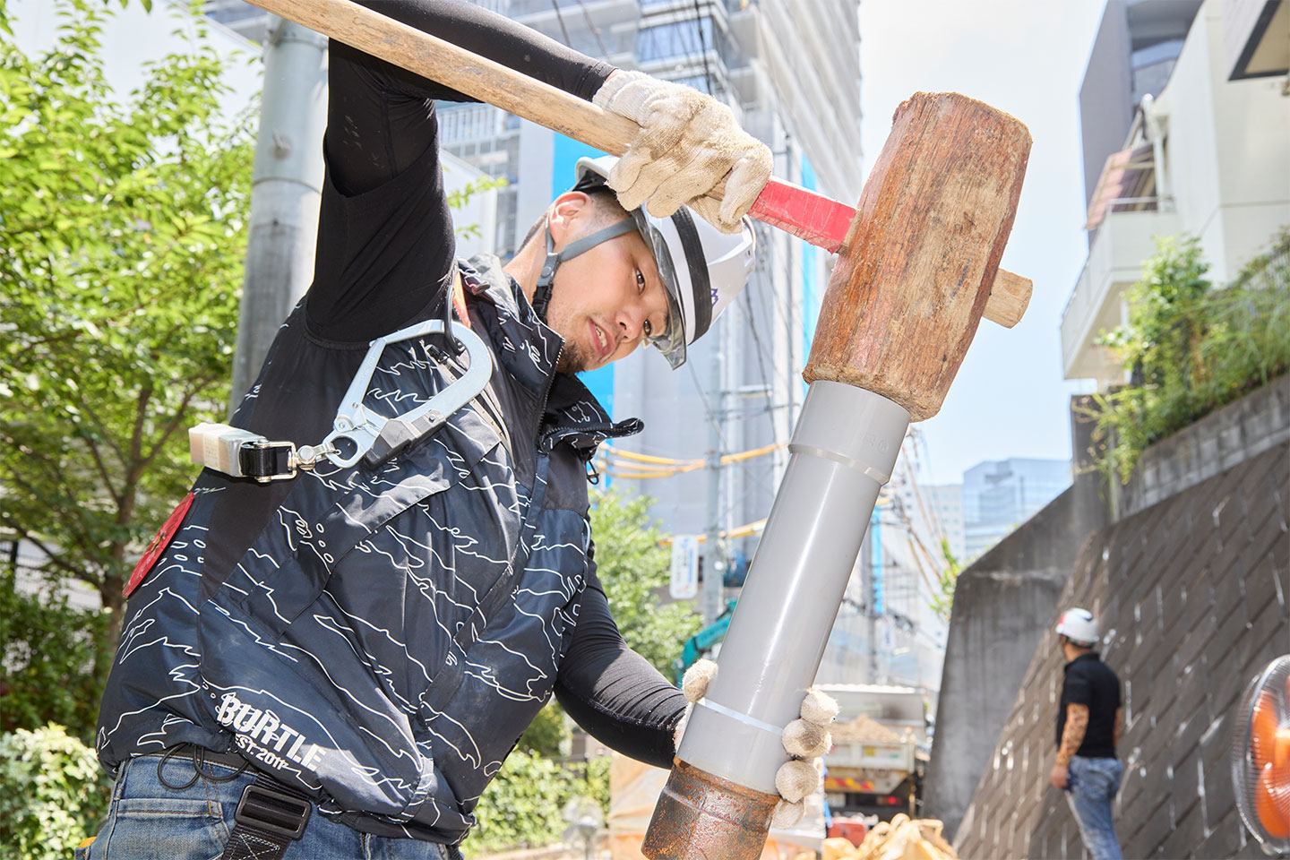 作業員が大きな木槌でパイプを叩いている様子
